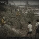 Two tiny humanoid figures in yellow suits hiding among bushes near Bukit Mertajam, Penang, Malaysia, August 1970