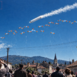 Archival-style illustration of the 1952 Oloron, France angel hair UFO case, showing a large tilted cylinder and dozens of red spheres over the town with falling white fibers