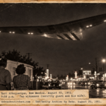 Vintage 1951 press photo style image of a silent swept-back flying wing with glowing lights gliding over a trailer home and Route 66 in Albuquerque