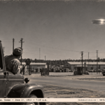 1950-style photo of two men in a truck watching a bright dishpan-shaped object over Red River Arsenal, Texarkana